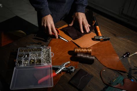 皮革工艺或皮革加工。皮革工作工具和切割棕色皮革在工匠的工作桌上。照片摄影图片_ID:349916779-Veer图库