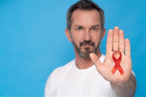 红色的艾滋病意识丝带持有男人灰色背景世界-包图企业站