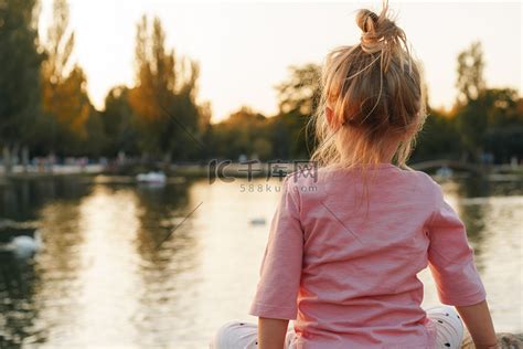 小女孩坐在湖边公园的一块巨石上高清摄影大图-千库网