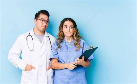 年轻医生夫妇在蓝色背景中装扮高清图片下载-正版图片503834825-摄图网