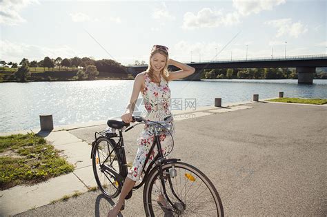 在纳多瑙河岛边骑自行车的年轻女人高清图片下载-正版图片501844863-摄图网