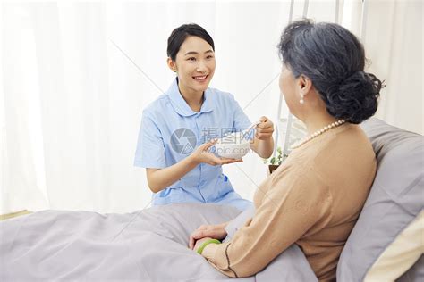 年轻女护工给卧床的老奶奶喂食高清图片下载-正版图片507608283-摄图网