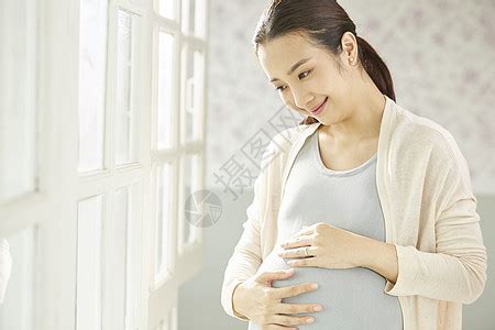 年轻孕妇看着宝宝的衣服高清图片下载-正版图片502347972-摄图网