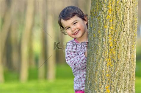 躲在森林里一棵树后面的小女孩女孩美女高清摄影大图-千库网