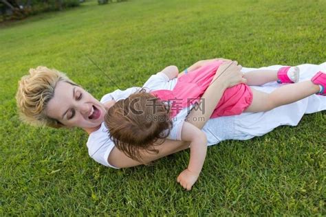 年轻的母亲和可爱的小女儿享受在后院草地上玩耍的空闲时间，自然概念中的幸福家庭高清摄影大图-千库网