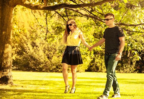 情侣在公园拉手年轻女孩和男一起散步夫妇在公园拉手高清图片下载-正版图片305080755-摄图网