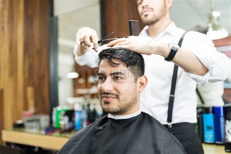 英俊的年轻帅哥在理发师身上做发型设高清图片下载-正版图片506299185-摄图网