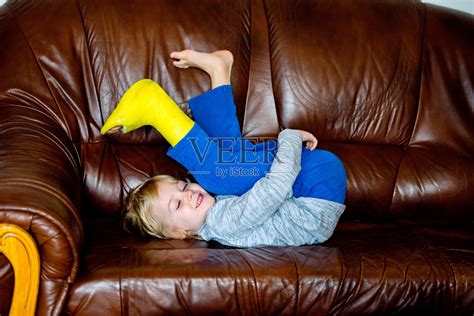 一个摔断了腿的男孩躺在沙发上。照片摄影图片_ID:126779430-Veer图库