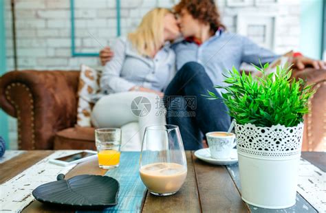 在咖啡桌上喝酒在背景中亲吻喝在咖啡桌上亲吻高清图片下载-正版图片303406770-摄图网