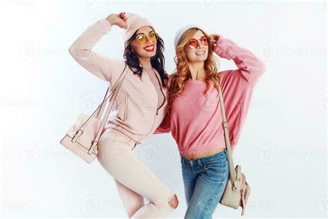 Indoor studio image of two girls, happy friends in stylish pink clothes ...