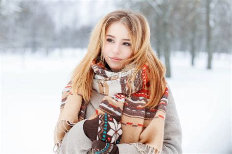 可爱的年轻迷人温柔女人与复古时尚围巾在时尚温暖的灰色外套与针织手套摆在公园冬季树木的背景上时高清图片下载-正版图片505775341-摄图网
