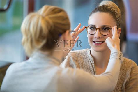 女售货员协助顾客戴眼镜照片摄影图片_ID:142230420-Veer图库