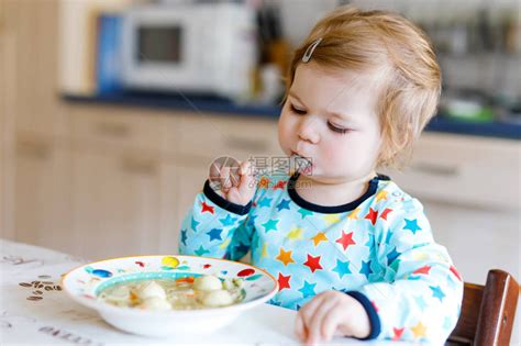 可爱的女婴从勺子蔬菜面条汤吃食物儿童喂养和发展理念可爱的蹒跚学步的女儿高清图片下载-正版图片502698867-摄图网