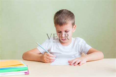 孩子坐在书桌上，在笔记本上写作业照片摄影图片_ID:391845652-Veer图库