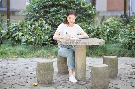 校园里坐在石凳上读书写字的女生高清图片下载-正版图片500702661-摄图网