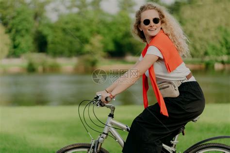 快乐女子骑着自行车在公园河道边高清图片下载-正版图片303741197-摄图网
