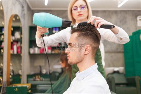 英俊的年轻帅哥在理发师身上做发型设高清图片下载-正版图片506299185-摄图网