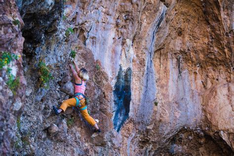一个女孩爬上岩石运动员在大自然中训练女人克服了艰难的攀登路线强壮的登山者极端的爱好高清图片下载-正版图片506587702-摄图网