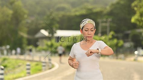 运动中年女性在锻炼期间在智能手表上检查健身结果或心率。高清摄影大图-千库网
