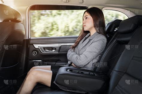 一位商务女性坐在汽车后座上用智能手机说话
