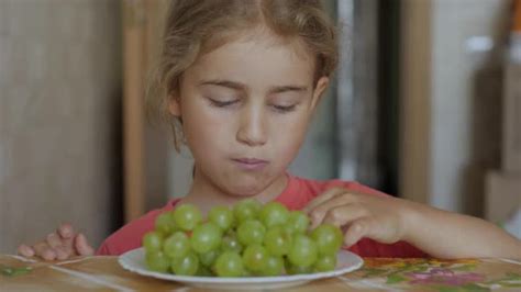 孩子吃甜葡萄。素食小女孩坐在厨房的餐桌上吃盘子里的白葡萄。健康有机素食。水果的收成。时间流逝。—高清视频下载、购买_视觉中国视频素材中心