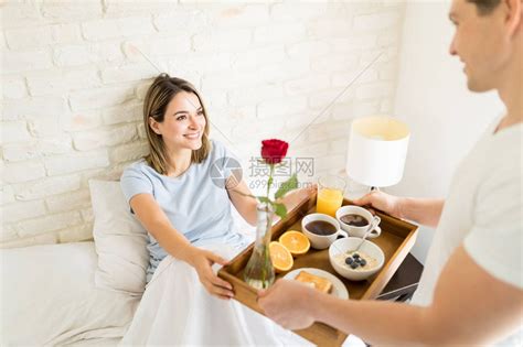微笑的年轻女人看着男朋友在她家里床上为她高清图片下载-正版图片503597179-摄图网