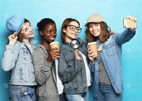 混血族群，由两个快乐的青少年、非洲裔美国女孩、白人男孩靠在墙上笑着一起喝外卖咖啡高清摄影大图-千库网