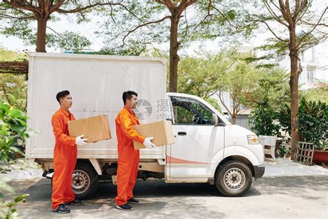 身着橙色制服装的送货服务工人携带箱子到客户高清图片下载-正版图片503800421-摄图网