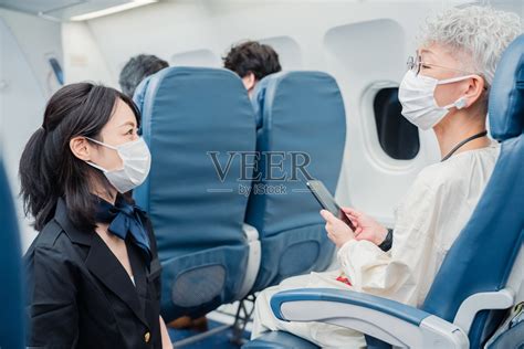 为戴口罩的乘客服务的空乘人员照片摄影图片_ID:429651934-Veer图库