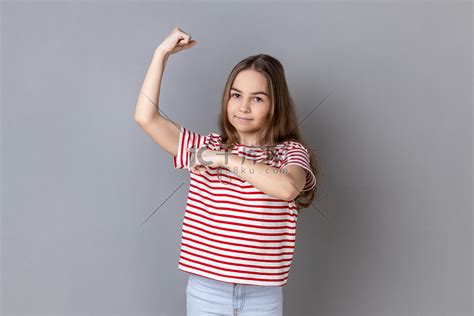 可爱的小女孩举起手指着二头肌，感受到实现目标的力量和能量。高清摄影大图-千库网