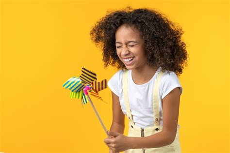 Premium Photo | Little girl laughing holding toy windmill isolated on ...