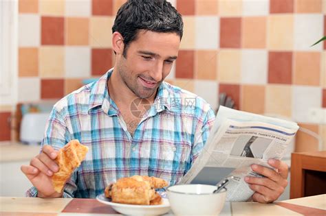男人边吃早餐边看报边看报纸糕点厨房阅读桌子咖啡勺子吸收面包可可羊角高清图片下载-正版图片321254788-摄图网
