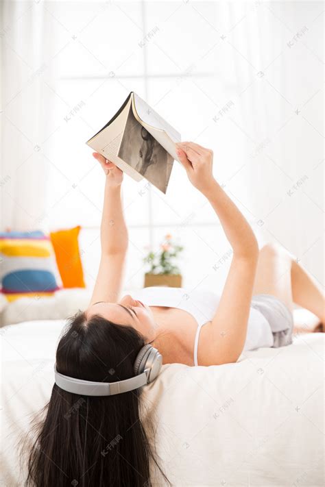 青年女人躺在床上听音乐看书高清摄影大图-千库网