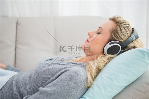 躺在沙发上听音乐的快乐女孩高清摄影大图-千库网