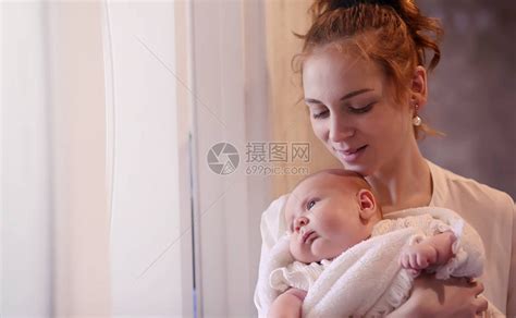 妈怀里抱着一个刚出生的婴儿女孩在窗前抱着一个婴儿母亲高清图片下载-正版图片506325090-摄图网