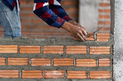 男砌砖工人用橡胶锤、水平尺和油灰刀安装内墙照片摄影图片_ID:328547630-Veer图库