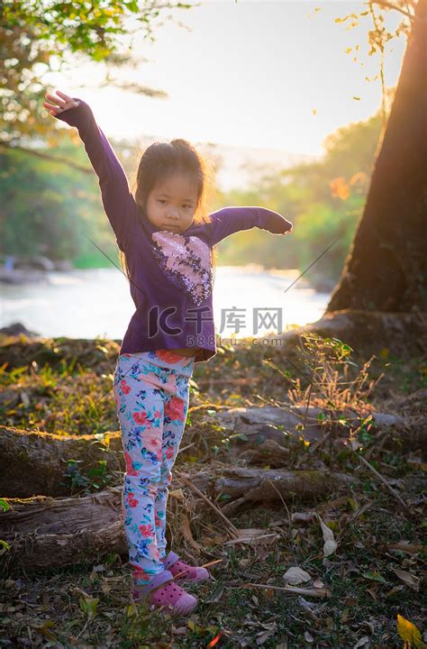 快乐的小女孩举起双手站在河边高清摄影大图-千库网