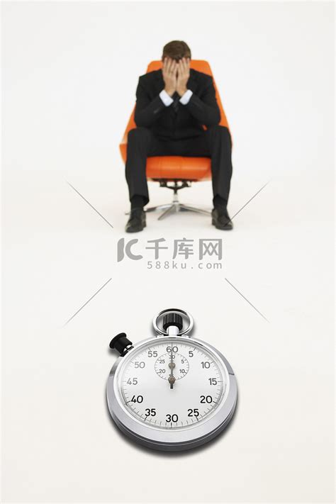 忧心忡忡的商人坐在椅子上，秒表代表时间的流失高清摄影大图-千库网