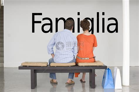 坐在长椅上的一对夫妇的近视 读意大利文本“Famiglia”(家庭)在墙上高清图片下载-正版图片321888809-摄图网