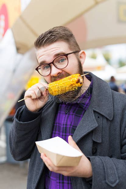 帅哥在街上吃着美味的玉米棒高清图片下载-正版图片506381818-摄图网