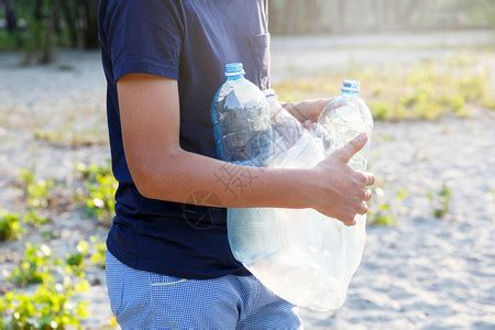 身穿蓝色T恤的志愿者男孩在公园捡起脏塑料瓶戴着黄色手套的手收集垃圾高清图片下载-正版图片506352284-摄图网