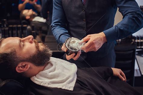 理发师在复古的氛围中给留胡子的人刮胡子高清图片下载-正版图片504879409-摄图网