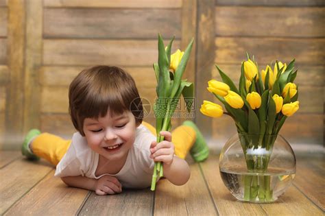 一个拿着一束黄色郁金香的小孩一个男孩拿着花瓶里的鲜花礼物女假期女孩的礼物高清图片下载-正版图片505459684-摄图网