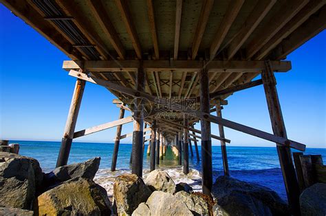 美国加利福尼亚州新港码头海滩 从下面岩石海洋海岸石头晴天蓝色假期码头波浪冲浪高清图片下载-正版图片321774223-摄图网